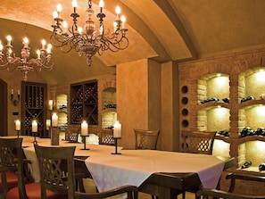 Comedor con candelabro, bodega de vinos y paredes de piedra.