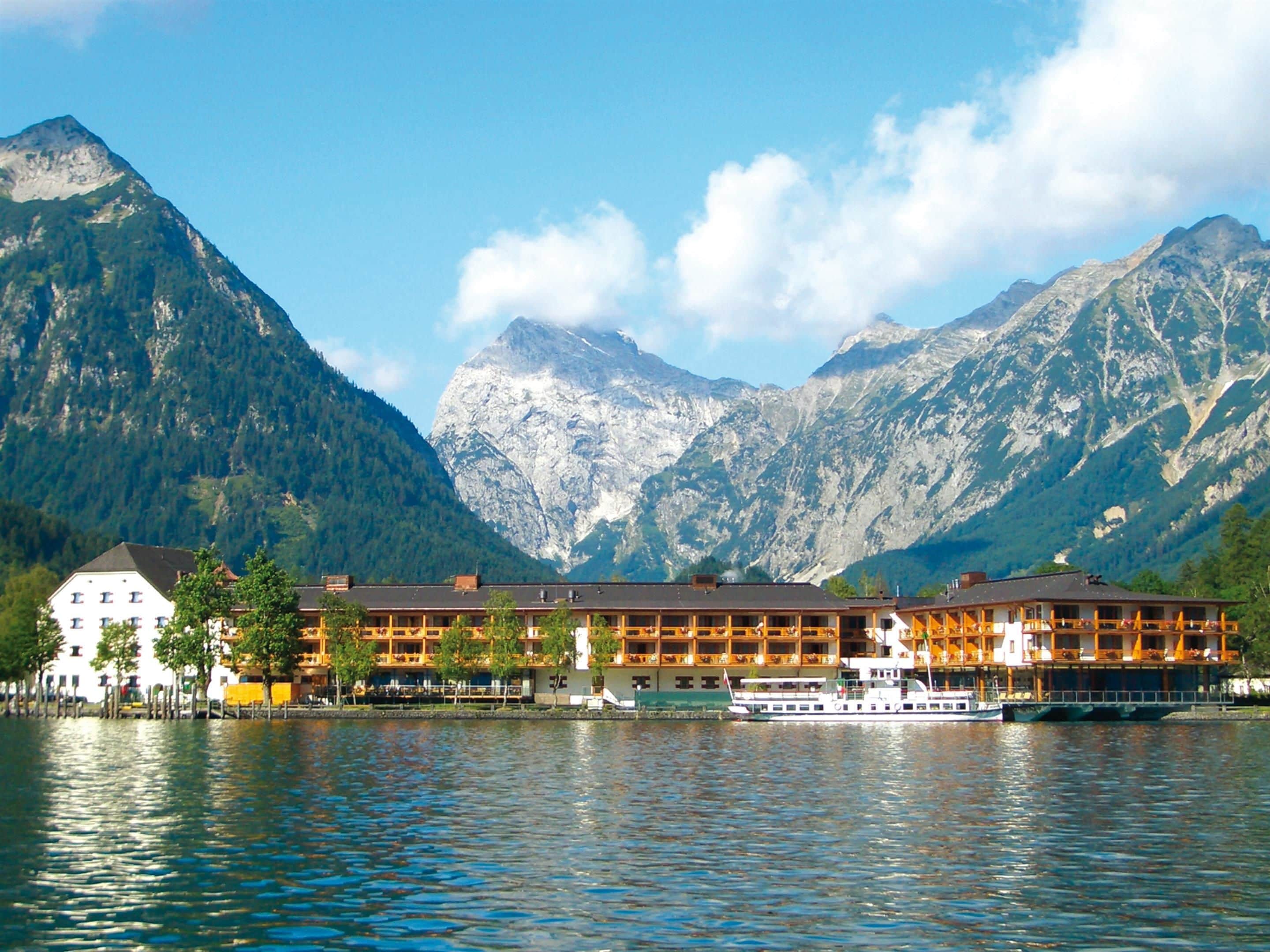 A lakeside hotel with a boat dock, surrounded by mountains.