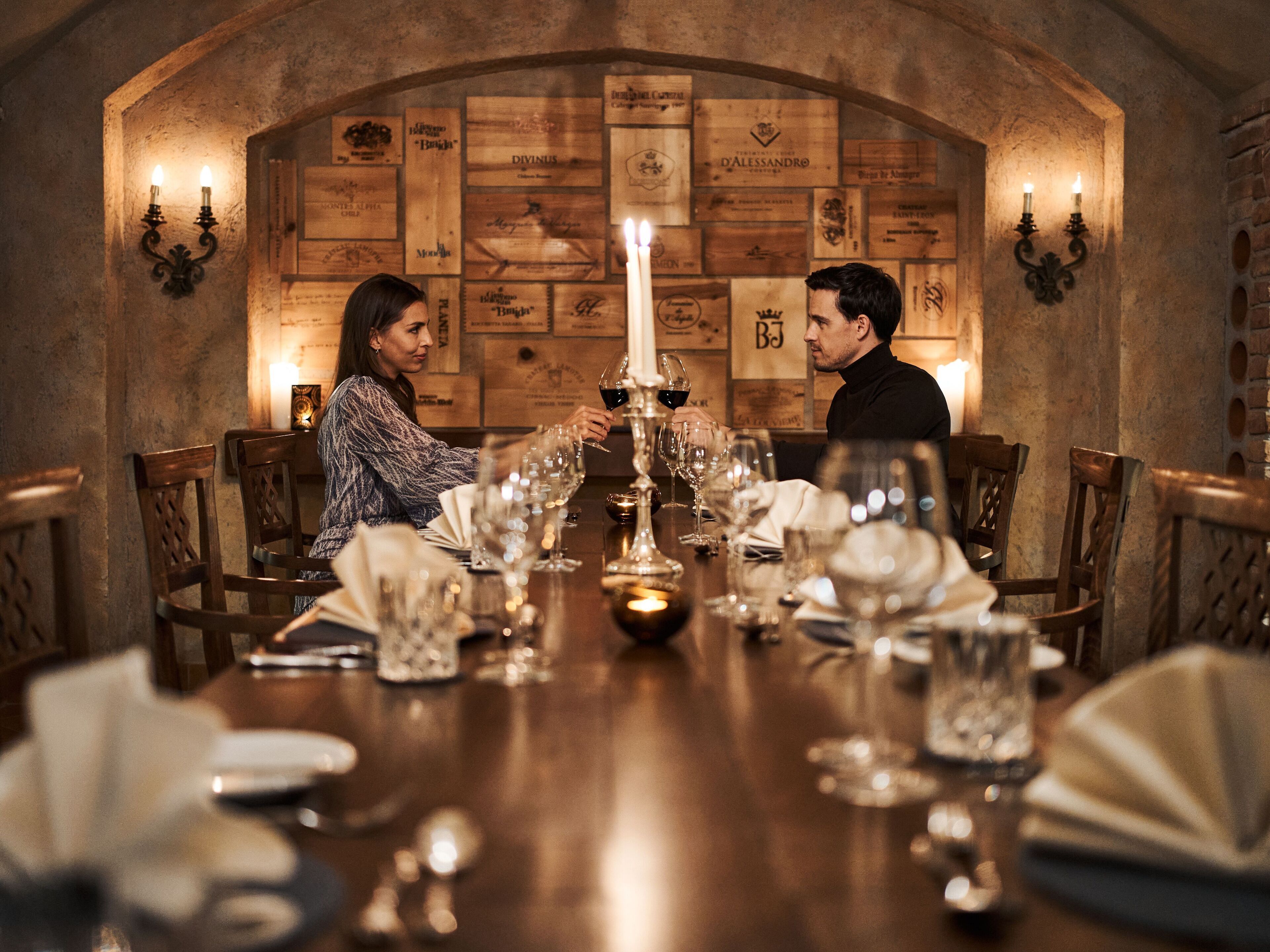 A dining table set with wine glasses, a candle, and a menu.