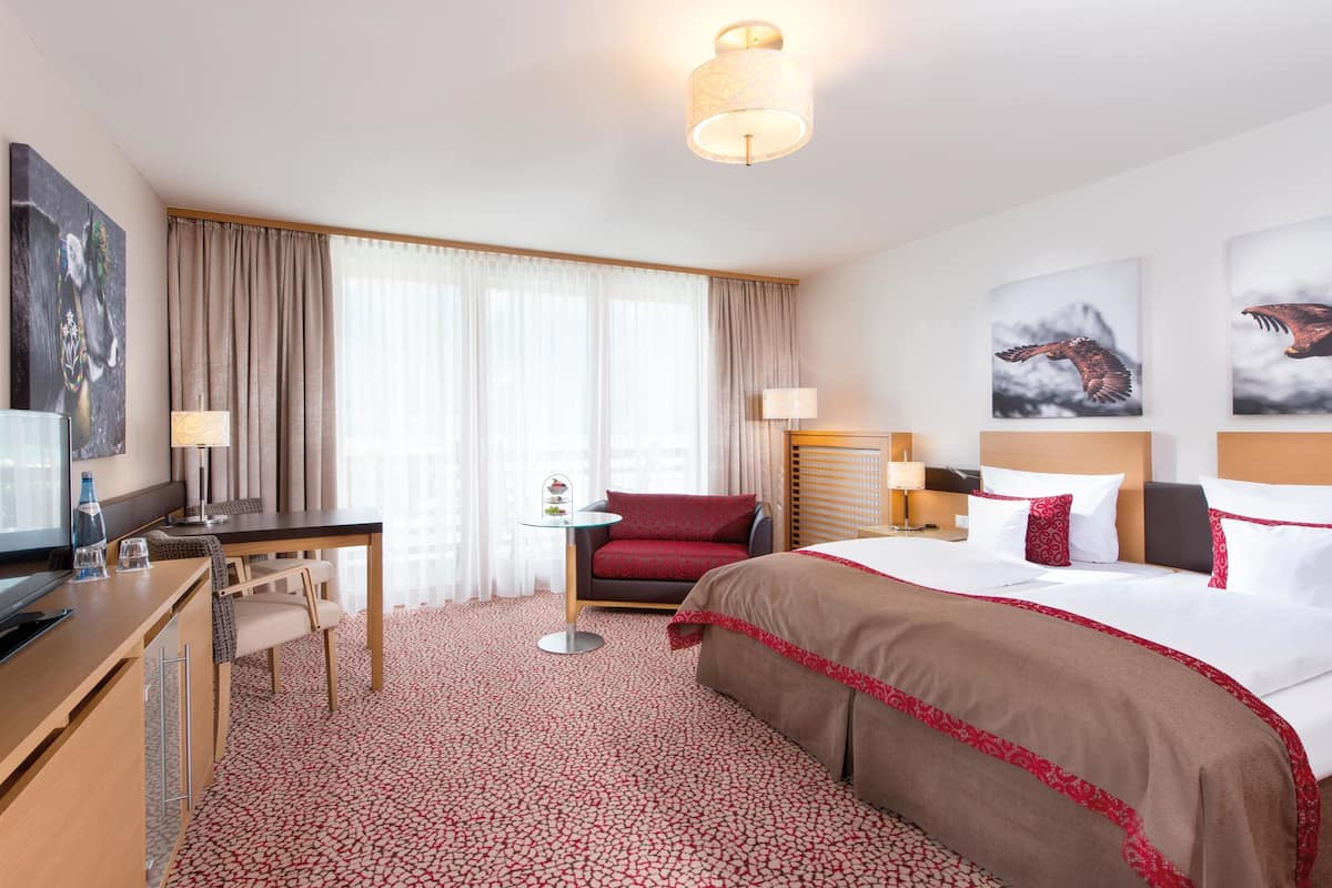 Une chambre d’hôtel avec un lit, un bureau, une chaise, une petite table et un téléviseur.