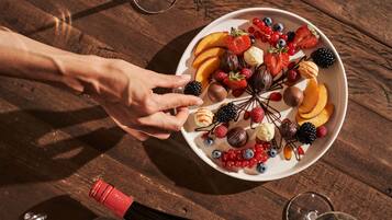 Une table en bois sur laquelle se trouve une assiette remplie de fruits variés et une bouteille de vin.