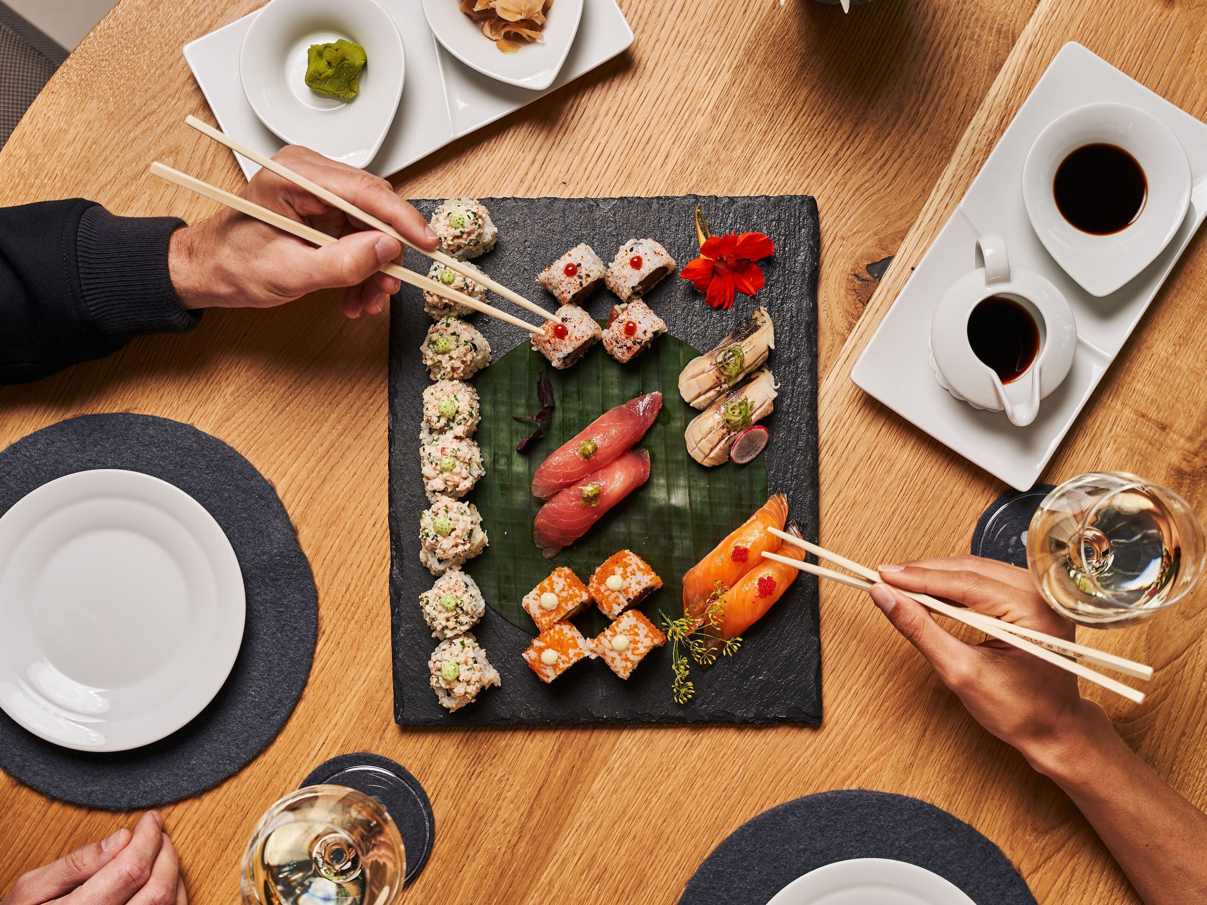 Une table où l’on trouve une variété de plats de sushis, des baguettes et des verres remplis de boissons.