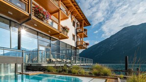Un hotel moderno con piscina, balcones con jardineras y vistas a la montaña.