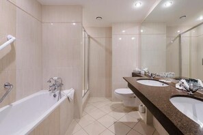 A modern bathroom with a bathtub, two sinks, a toilet, and a glass shower enclosure. - Shearwater Hotel & Spa (Ballinasloe)