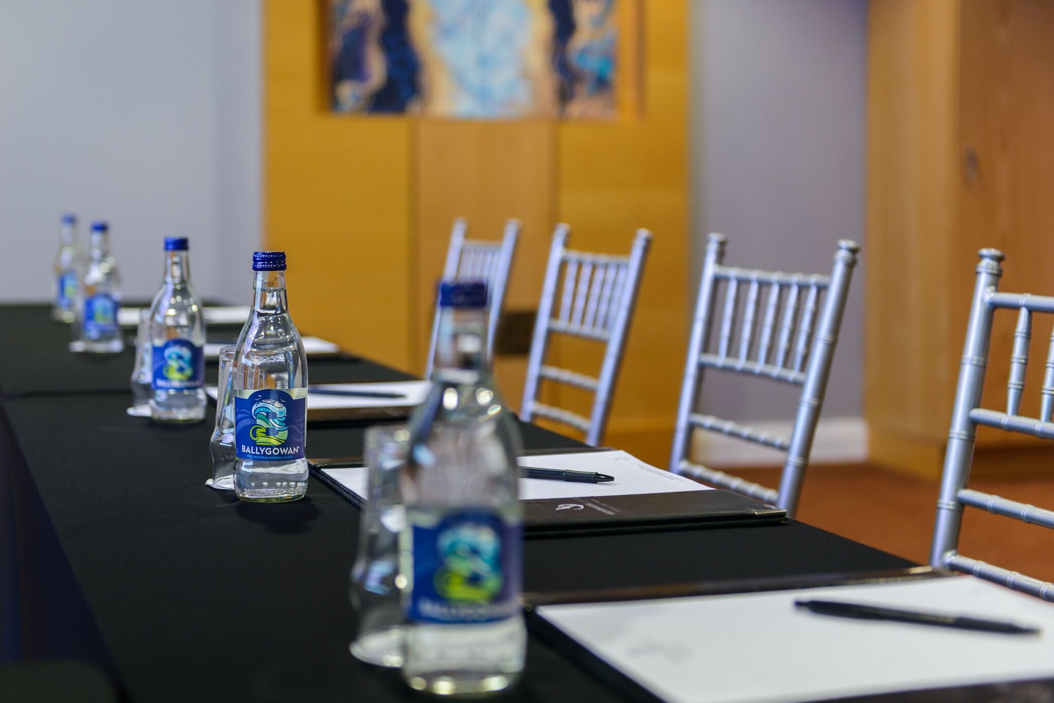 A conference table with water bottles, chairs, and documents.