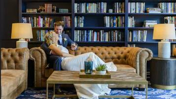 Un'accogliente area relax con un divano trapuntato, un tavolino da caffè e una libreria piena di libri.