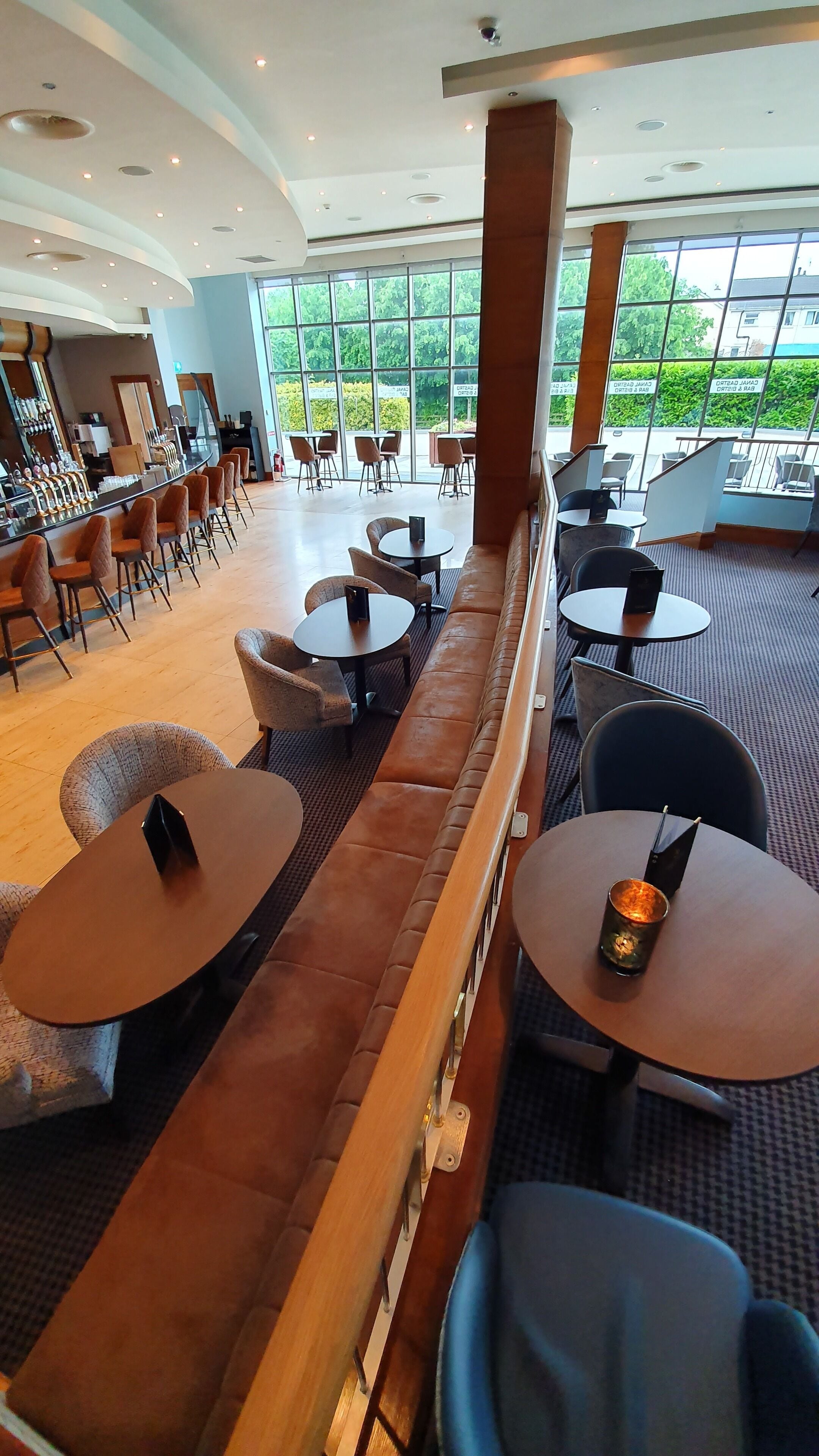 A modern indoor seating area with a long bench, round tables, and chairs.