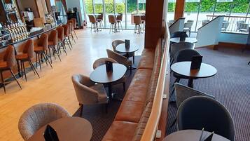 A modern indoor seating area with a long bench, round tables, and chairs.