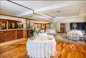 A hotel lobby with a round dining table set for a formal event, a reception area with a bar, and a large chandelier. - Shearwater Hotel & Spa (Ballinasloe)