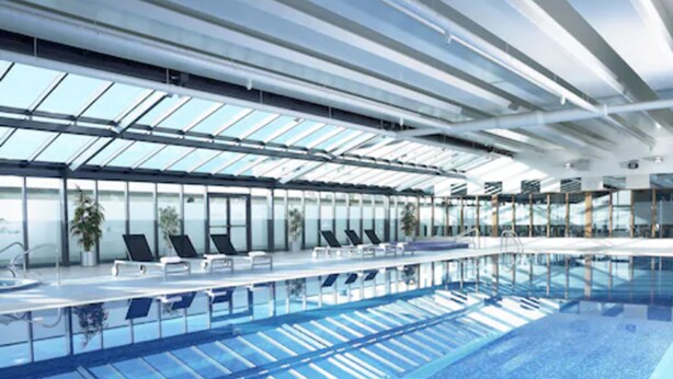 A modern indoor swimming pool with clear glass ceilings and lounge chairs along the poolside. - Shearwater Hotel & Spa (Ballinasloe)