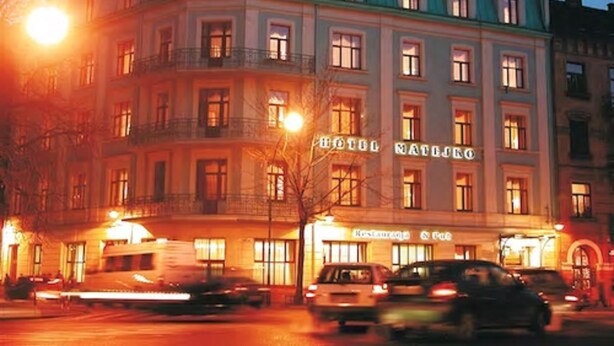 Hotel com estilo arquitetônico clássico, com uma placa de destaque e um restaurante no nível da rua.