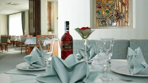 Uma mesa de jantar posta com uma garrafa de vinho Breguet Rose, uma taça de martini e guardanapos dobrados.