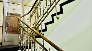 Uma escadaria com grades de metal ornamentadas e um padrão preto em zigue-zague na parede.