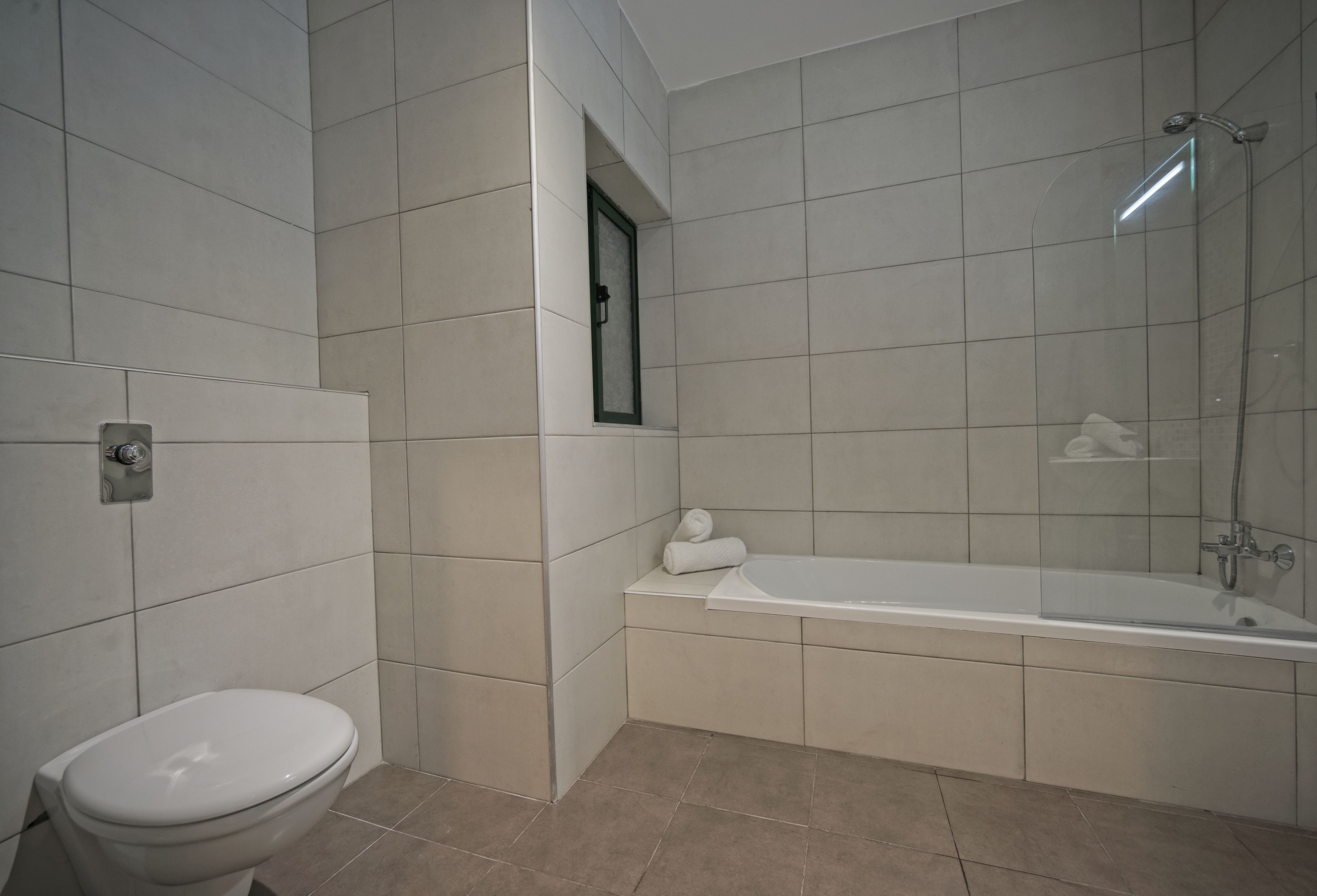 A modern bathroom with a toilet, a bathtub, and a shower.