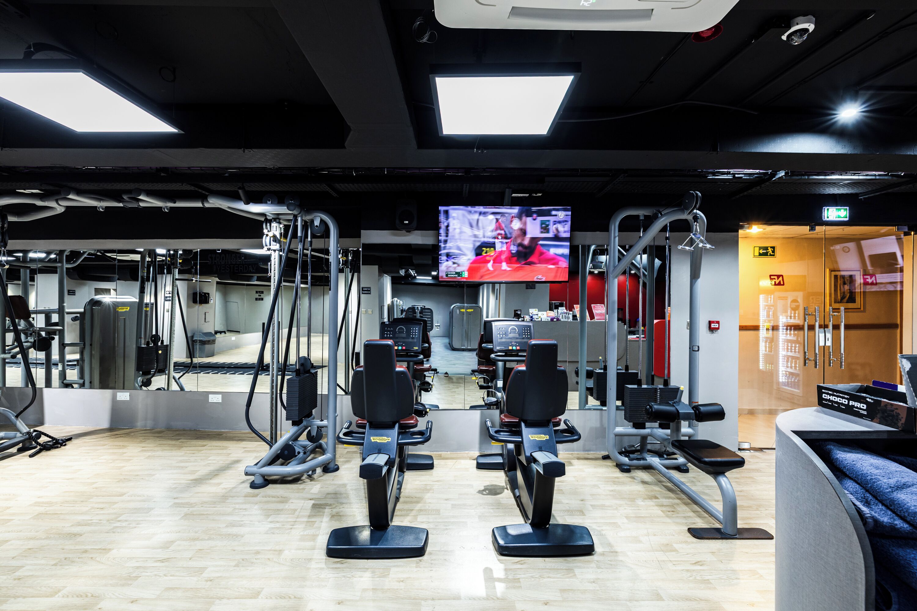 A gym with exercise equipment, a TV screen, and a mirror.