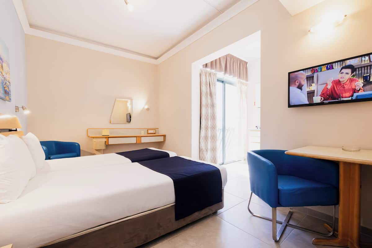 Een hotelkamer met een bed, bureau, stoel en televisie.