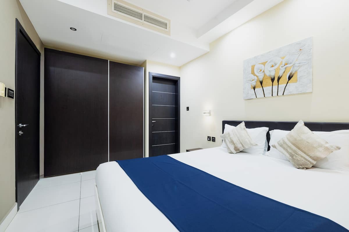 Een hotelkamer met een groot bed, een donkerhouten garderobe en een schilderij aan de muur.