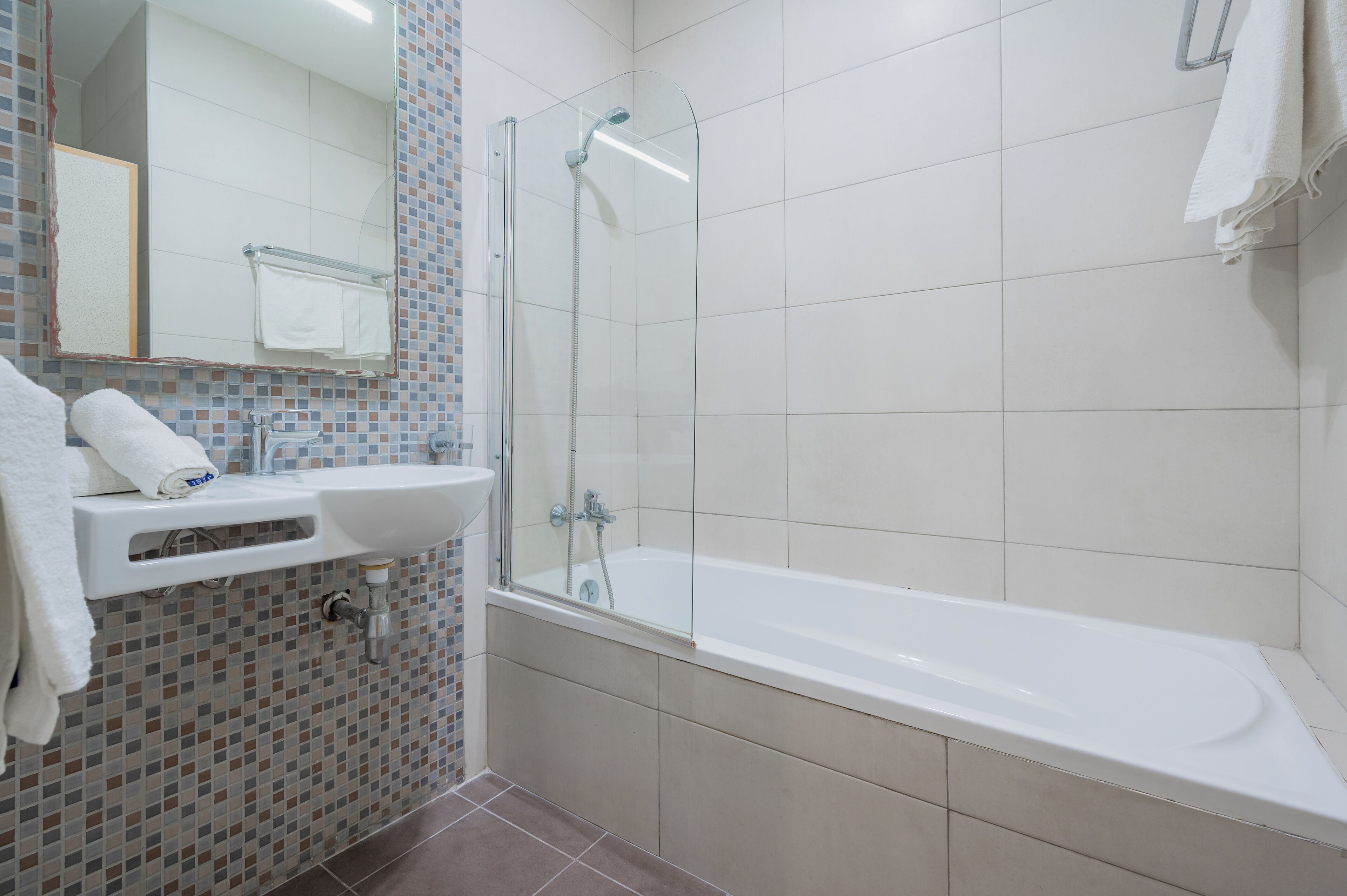 Ein modernes Badezimmer mit einer gläsernen Duschkabine, einem weißen Waschbecken und einer Badewanne.