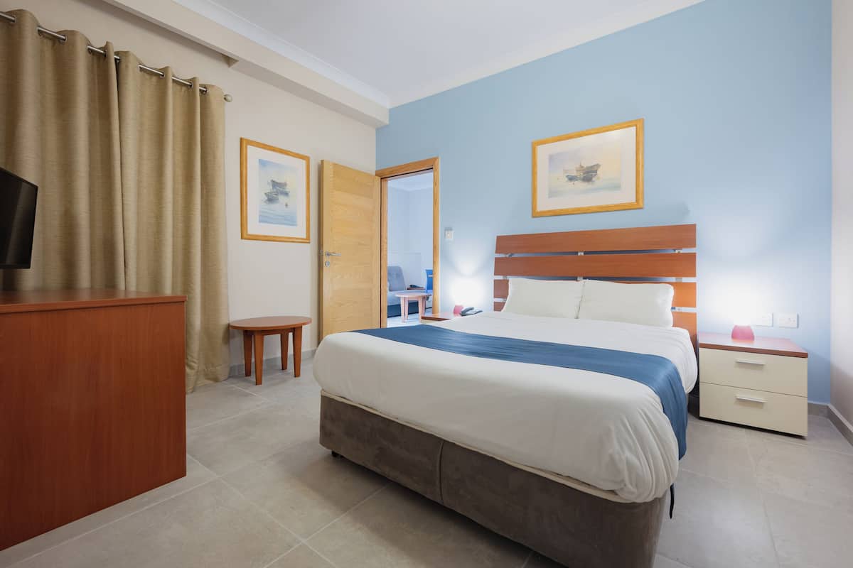 Een slaapkamer met een bed, nachtkastje en bureau.