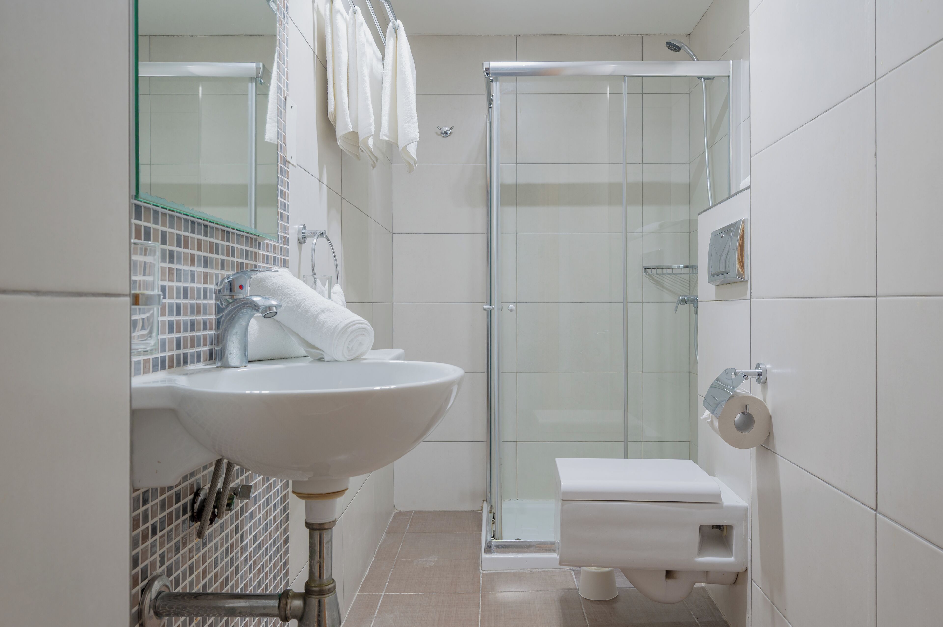 Uma casa de banho moderna com uma sanita, um lavatório branco e um chuveiro com cabine de vidro.