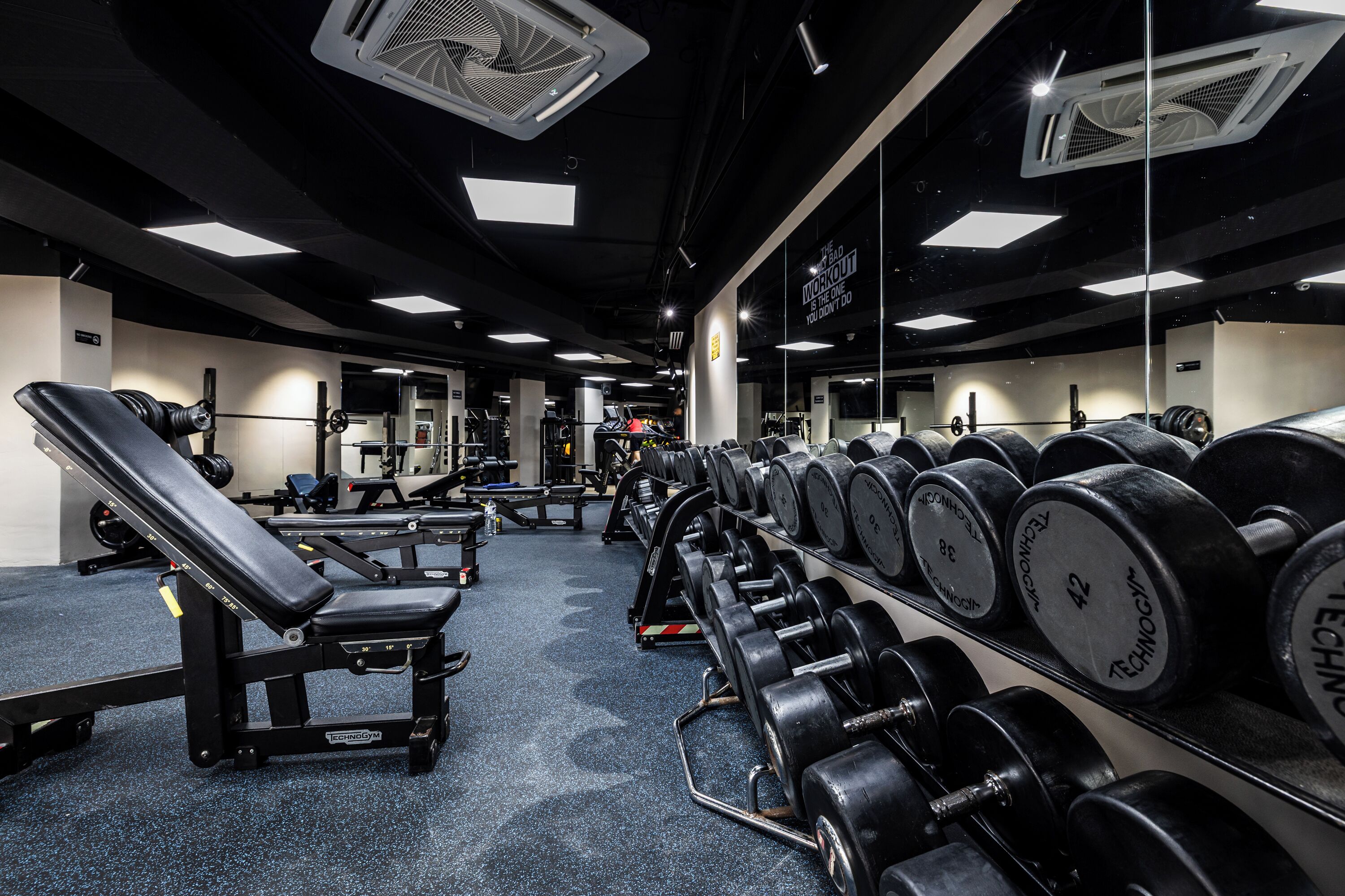 A gym with weightlifting equipment, benches, and mirrors.