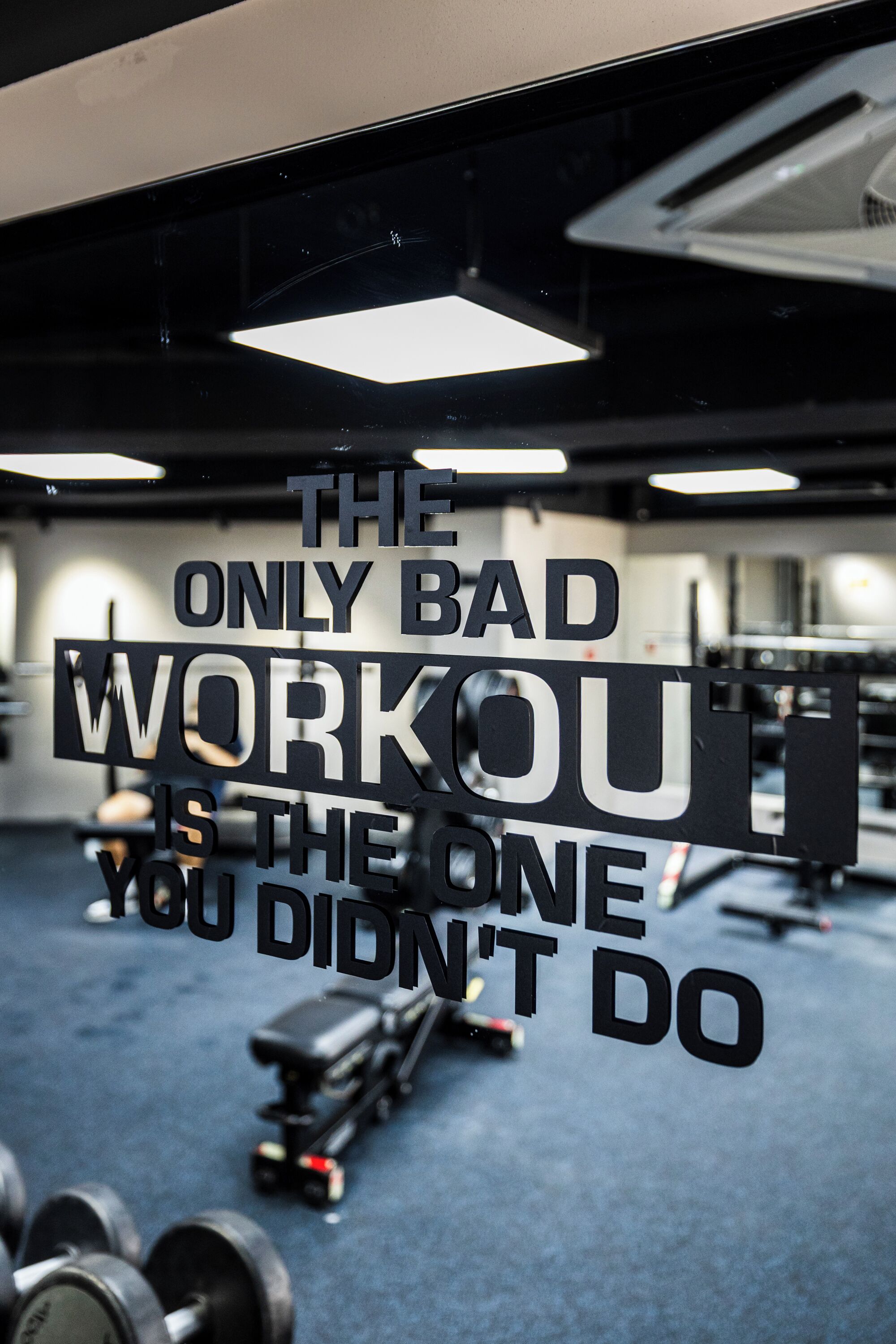 Un gimnasio con frases motivacionales en la pared y equipo de ejercicio.