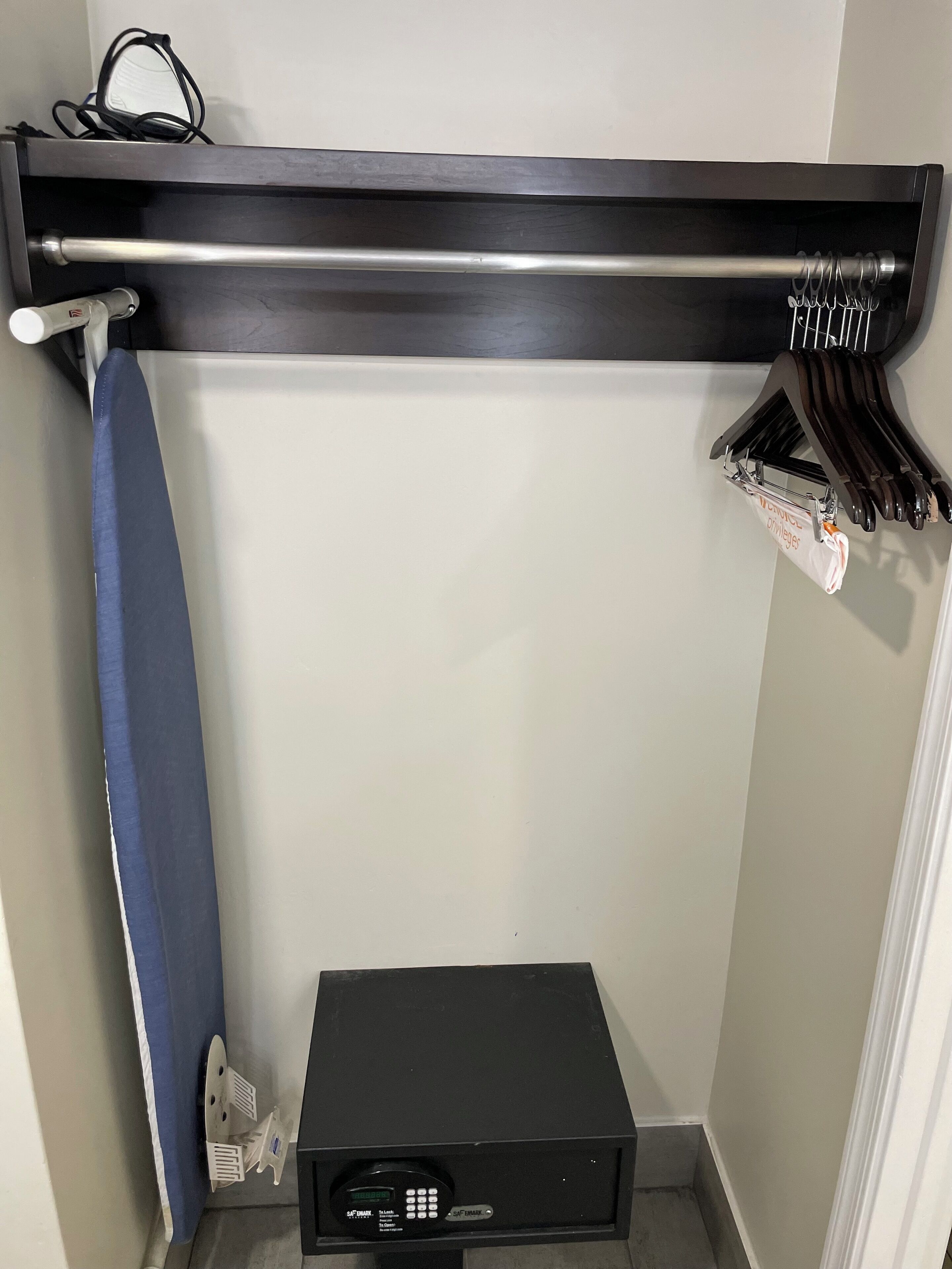 Une petite pièce avec un radiateur noir, une serviette bleue et un porte-vêtements avec des cintres.