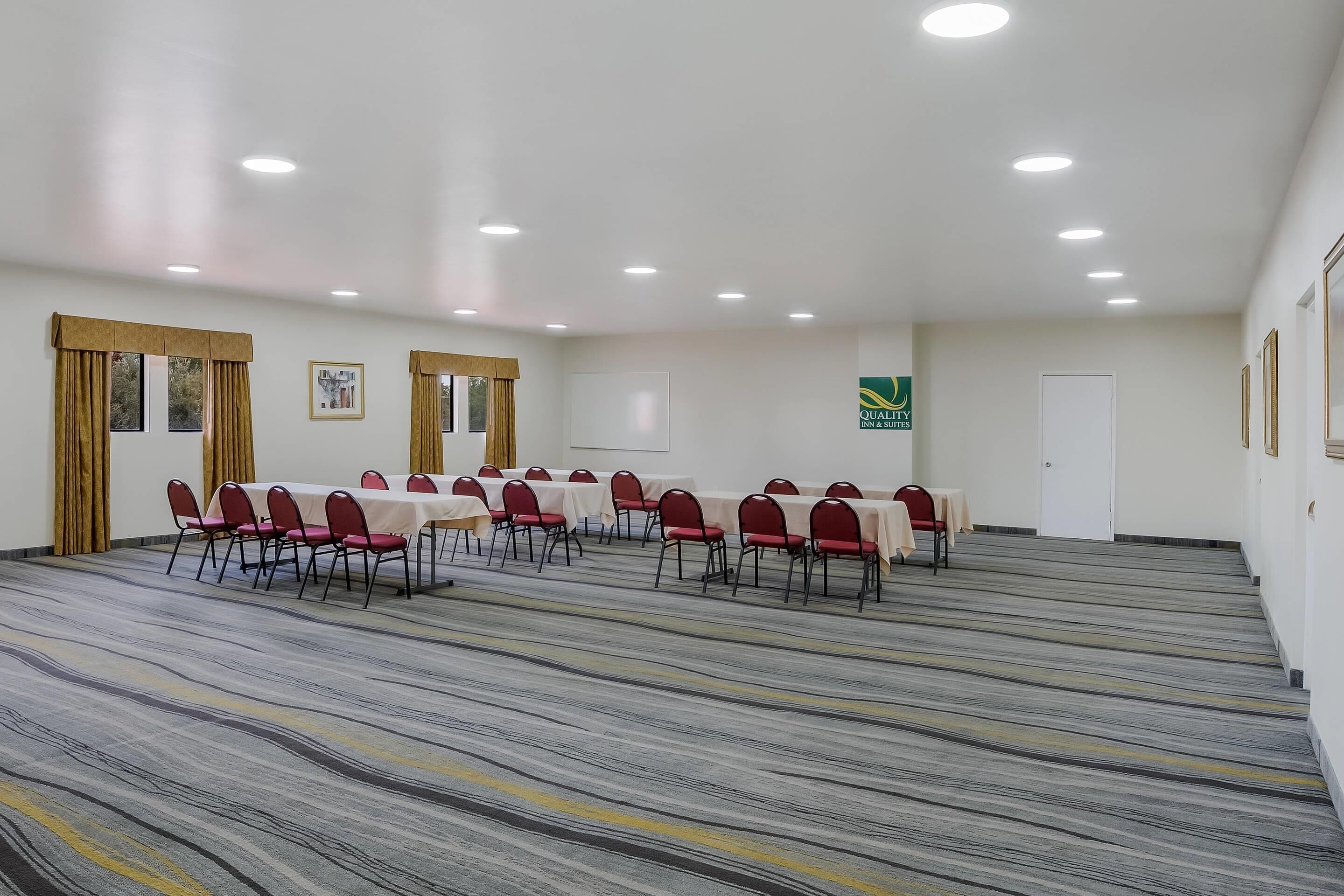 Un salón de conferencias con suelo alfombrado, mesas y sillas, y una puerta.