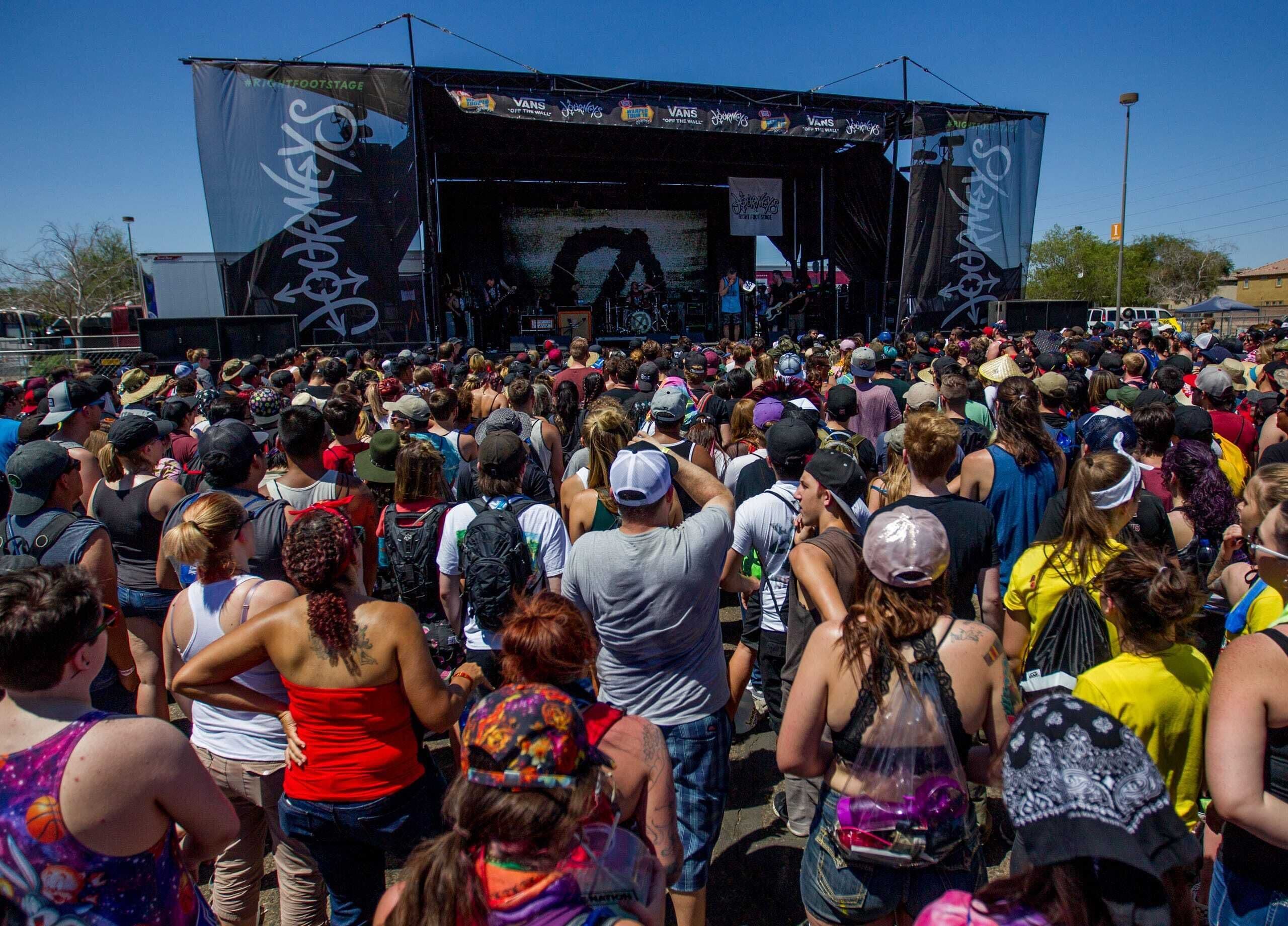 A crowded outdoor event with a stage and banners.