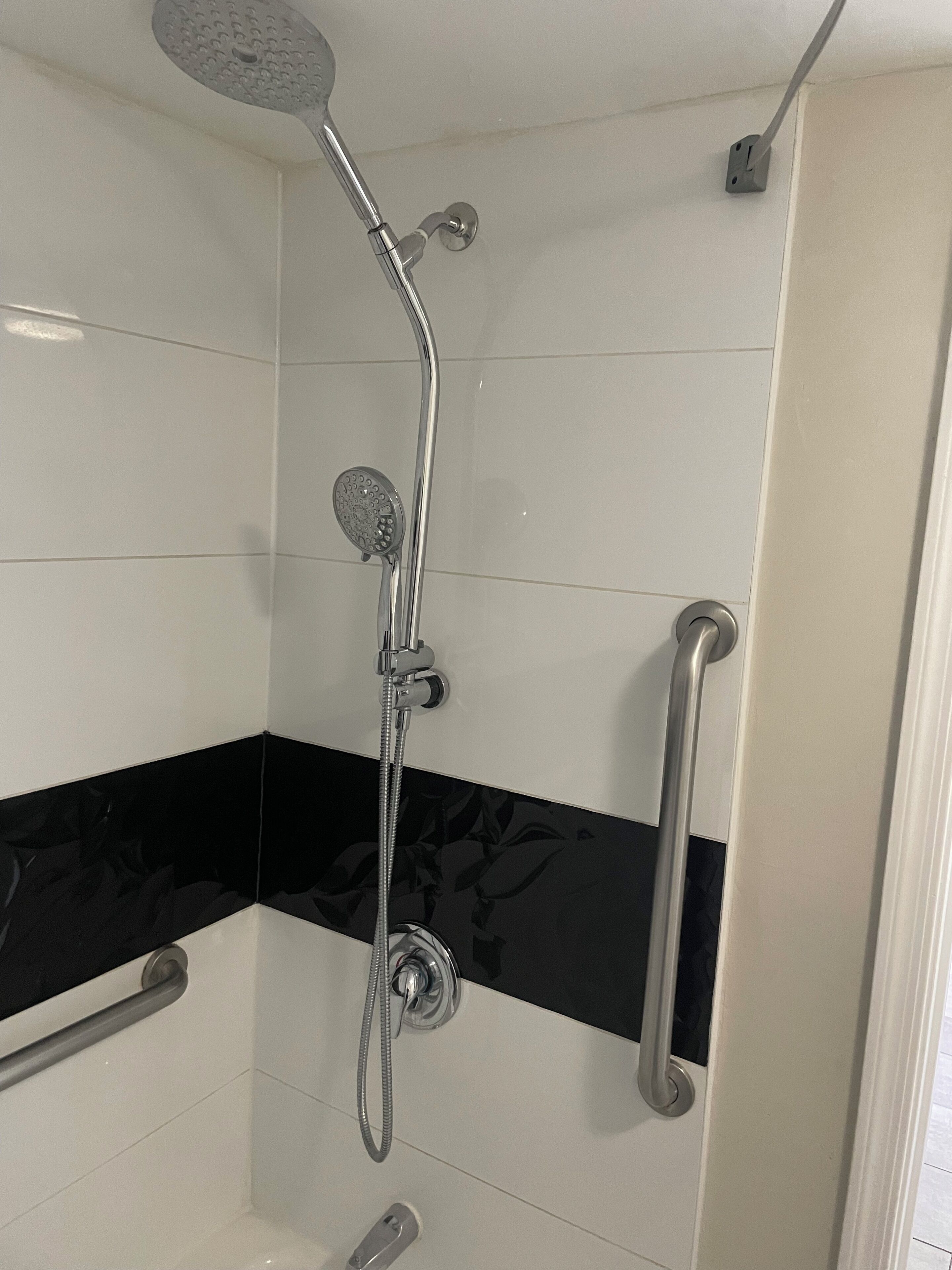 Una ducha con cabezal de ducha de mano, grifo empotrado en la pared y cabezal de ducha de mano.
