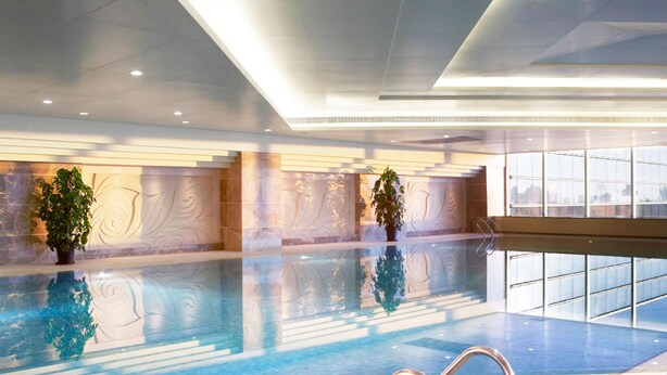 An indoor swimming pool with clear water, surrounded by a modern interior with decorative wall panels and potted plants. - Shangri-La Baotou (Baotou)