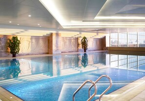 An indoor swimming pool with clear water, surrounded by a modern interior with decorative wall panels and potted plants. - Shangri-La Baotou (Baotou)