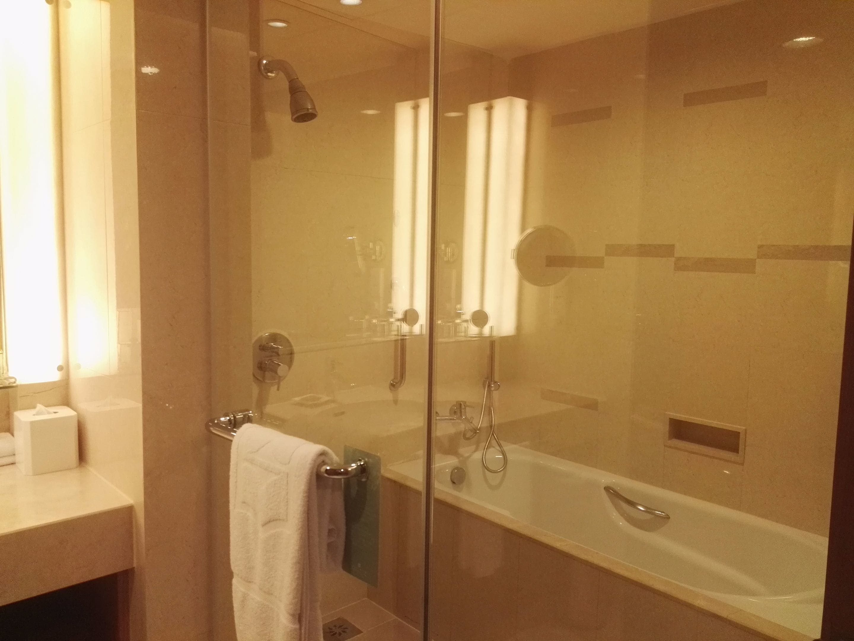 A modern bathroom with a glass-enclosed shower, a bathtub, and a vanity with a towel rack.