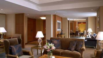 Un amplio vestíbulo de hotel con un sofá marrón, sillones, una mesa de centro con tazas y un jarrón de flores, además de una araña.