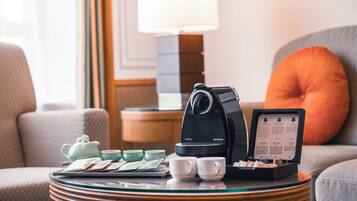 Eine Kaffeemaschine, ein Teekessel, Tassen und eine Speisekarte stehen auf einem Tisch in einem Hotelzimmer.