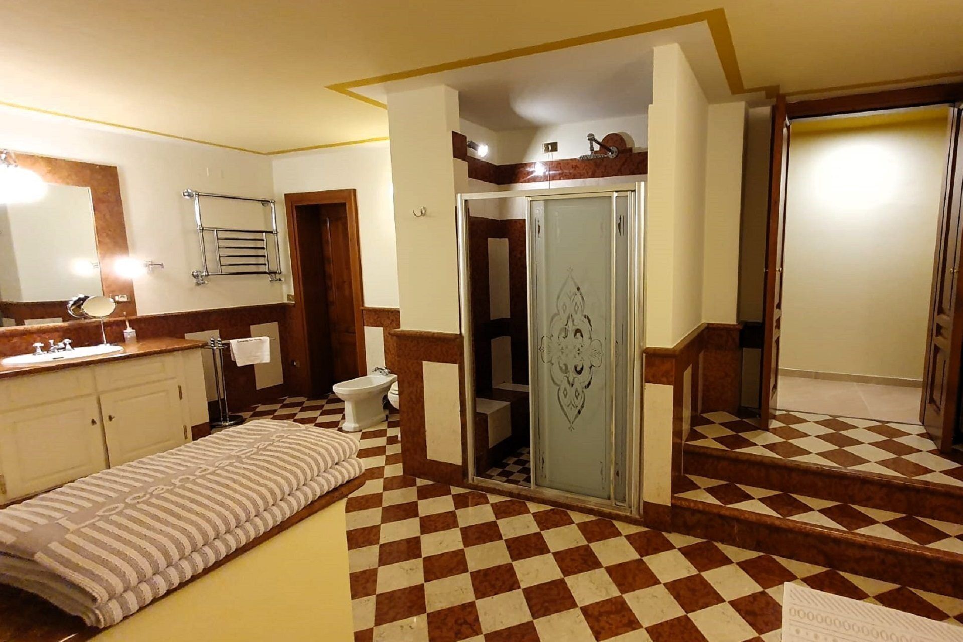 Een badkamer met een geruit vloertje, een wastafel met spiegel, een douchetoilet en een handdoekhouder.