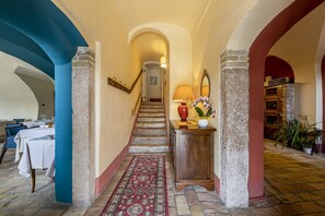 A hallway with a staircase, a wooden console table with a lamp, a mirror, and a red patterned rug. - Resort Locanda San Verolo Boutique Hotel (Costermano sul Garda)