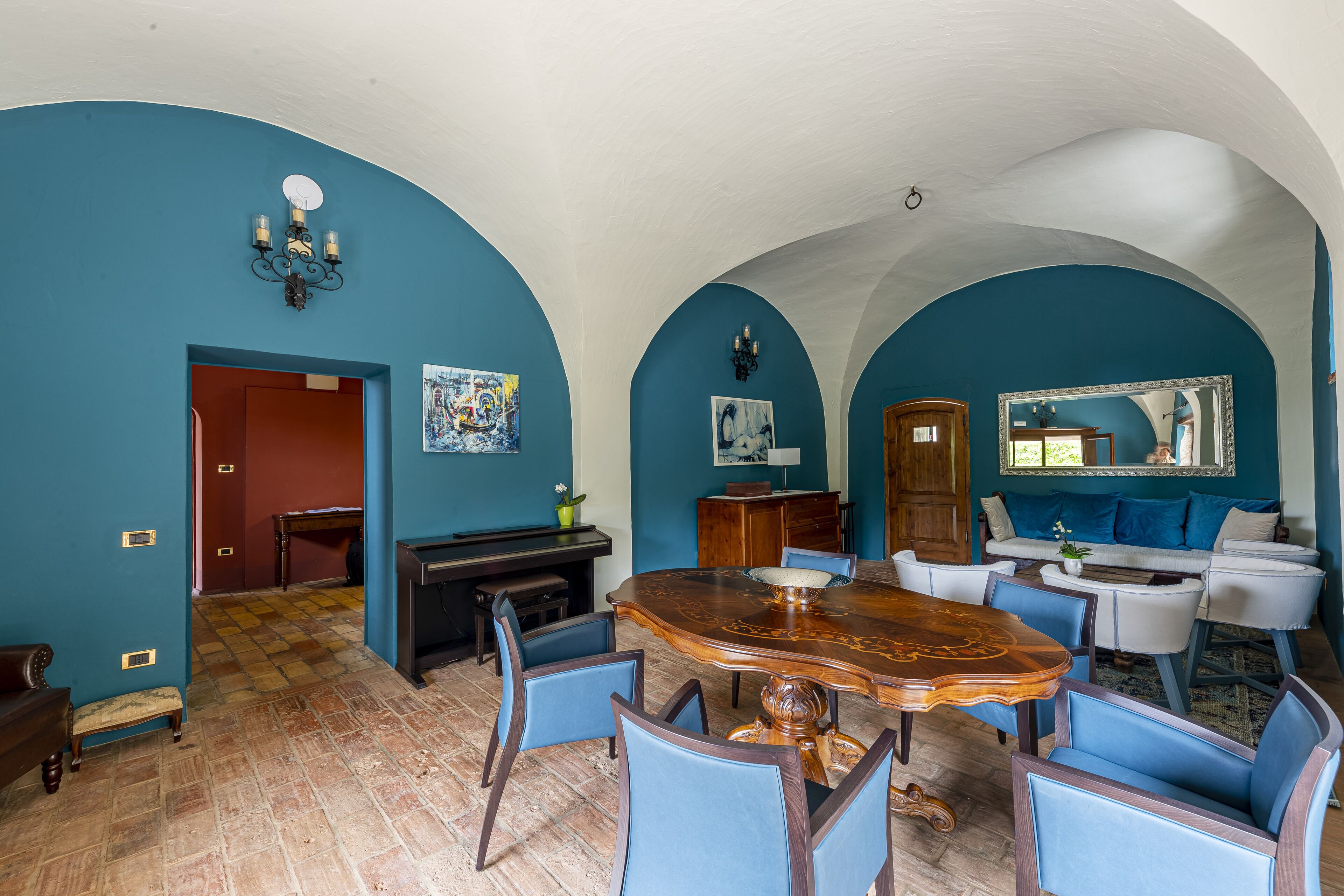 Ein Essbereich mit einem großen Holztisch, blauen Stühlen und einer Chandelüster.
