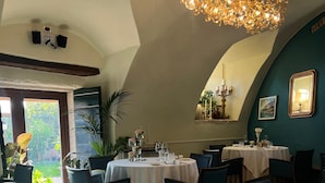 A dining area with tables set for two, a chandelier, and a view of greenery outside. - Resort Locanda San Verolo Boutique Hotel (Costermano sul Garda)