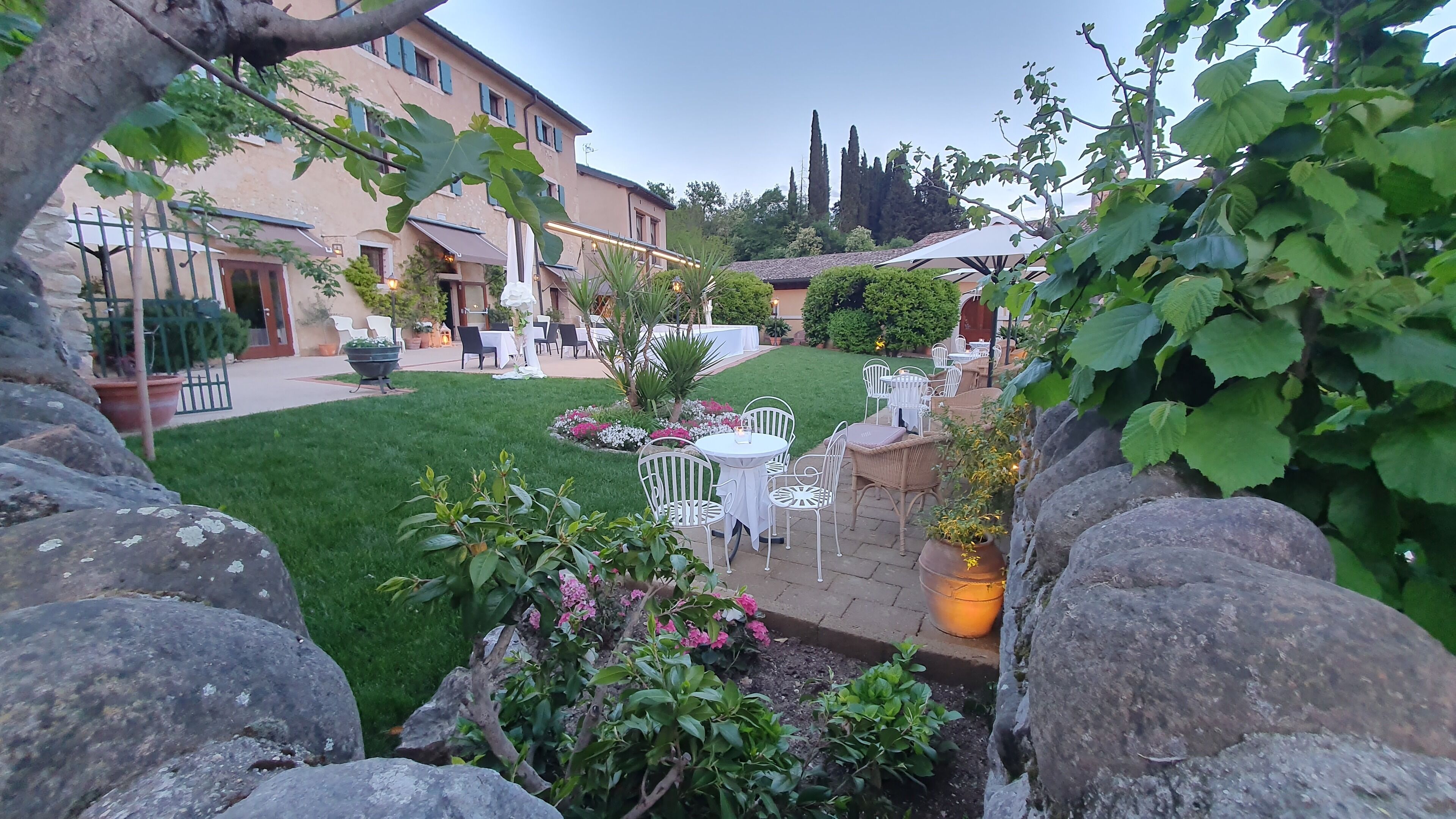 Un patio con mobiliario exterior, césped cuidado y un edificio al fondo.
