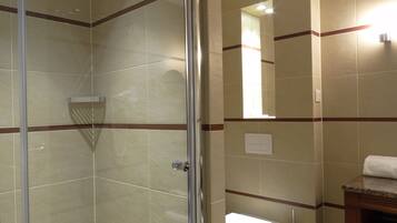A bathroom with a glass shower enclosure, a toilet, and a sink with a wooden countertop.