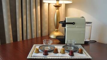 Une table avec une machine à café, un plateau avec des tasses et des chocolats, et une lampe.