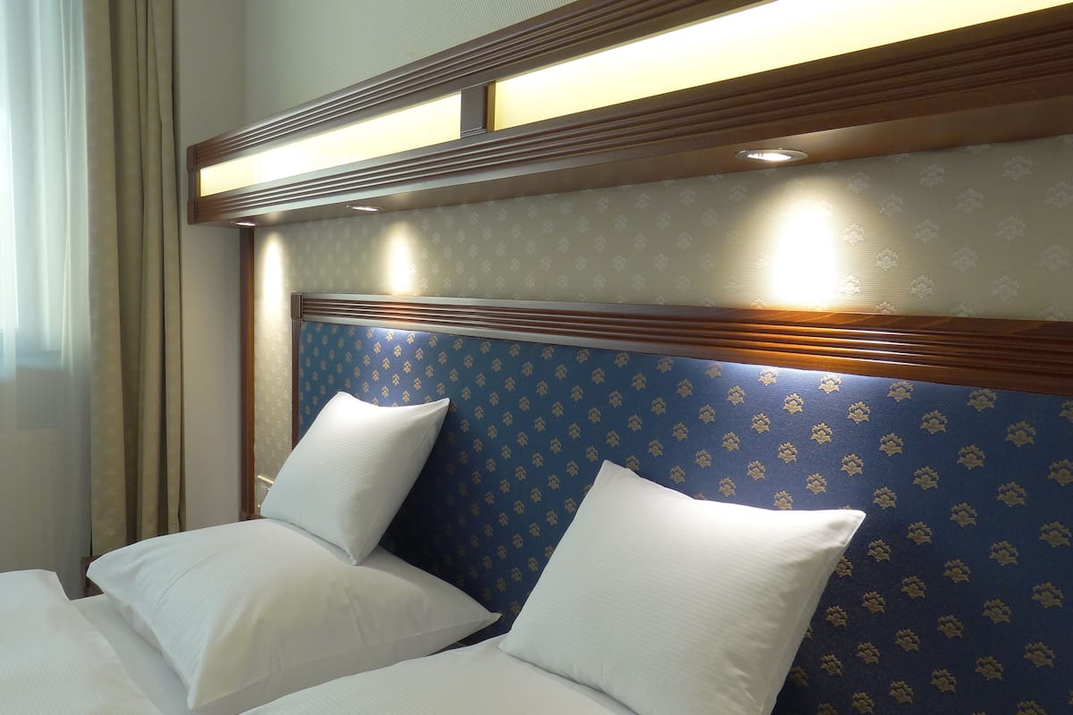 Ein Hotelzimmer mit einem großen Bett, zwei Kissen und einem Kopfteil mit einem gemusterten Design.