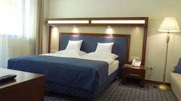 A hotel room with a bed, bedside tables, a lamp, and a phone.
