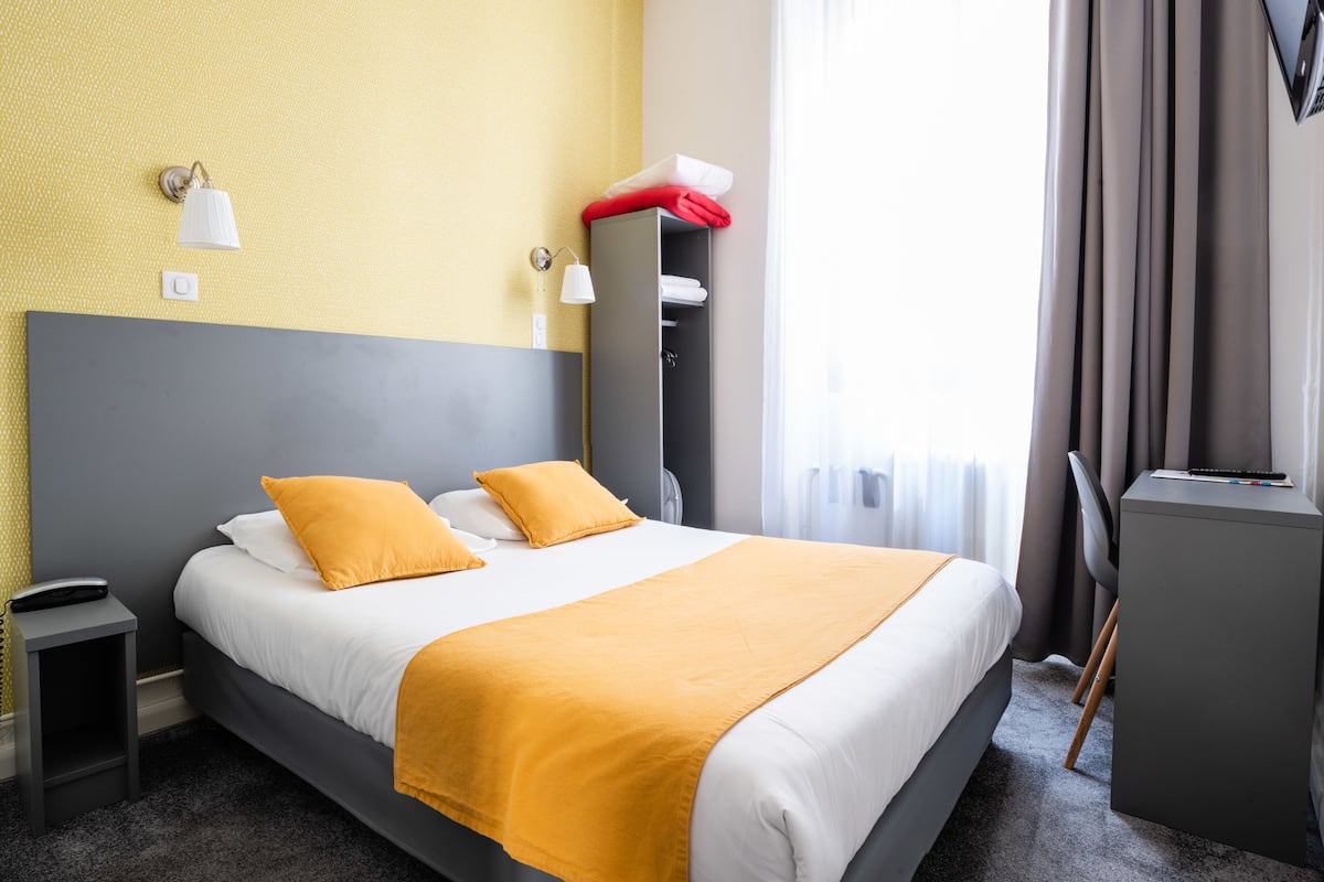 A hotel room with a bed, a desk, and a wardrobe.
