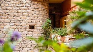 A stone wall with a small window, potted plants, and a reflection in the water. - Hotel Au Patio Morand (Lyon)