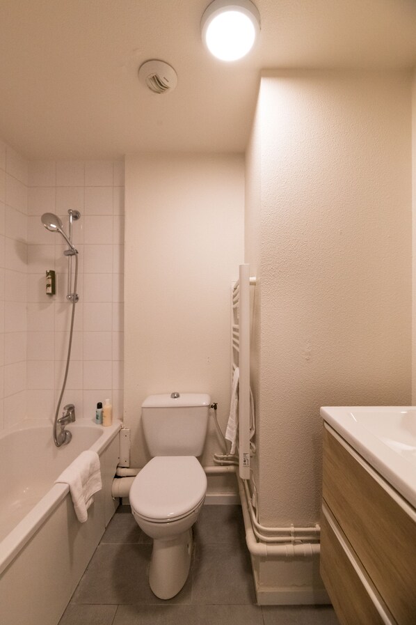 A compact bathroom with a bathtub, toilet, and shower.
