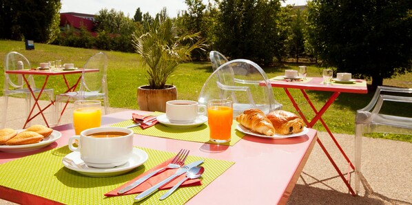 An outdoor dining setup with clear chairs, a table, and a potted plant.