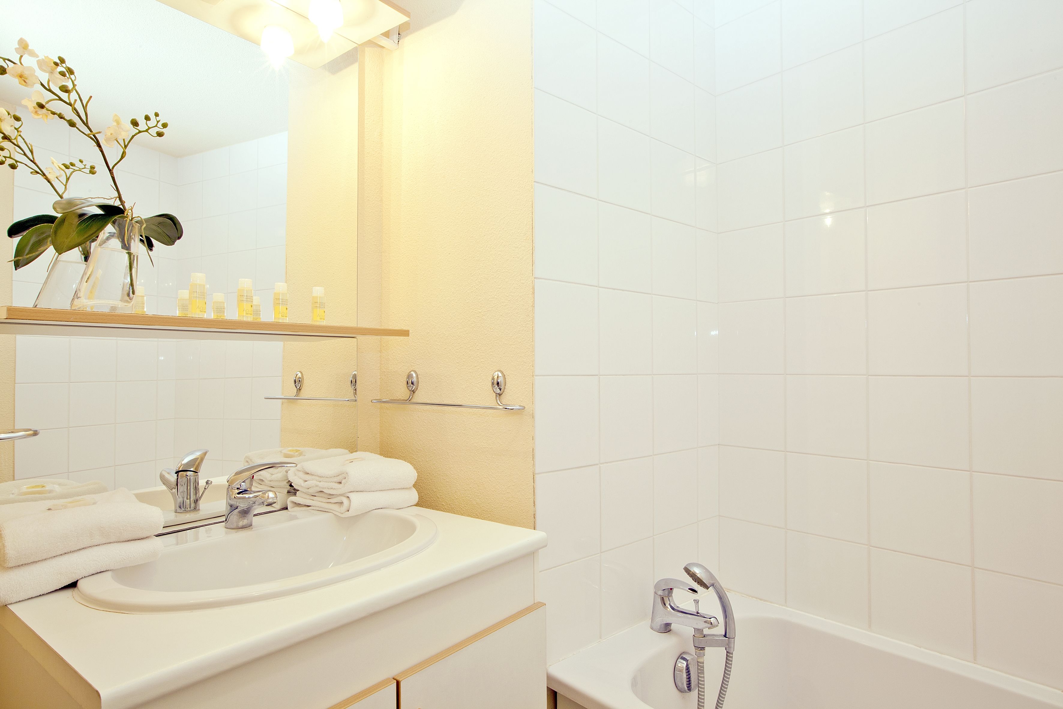 A modern bathroom with a white sink, mirror, and bathtub.