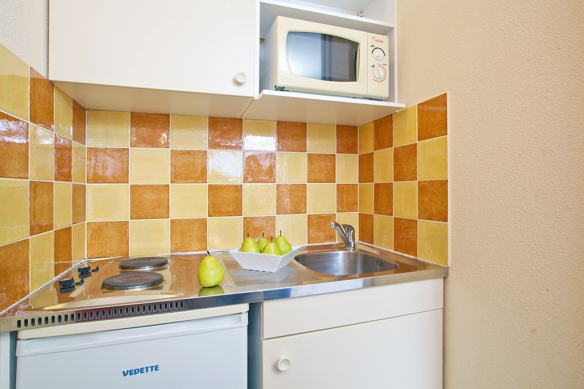 Una cocina con estufa, lavamanos y microondas.